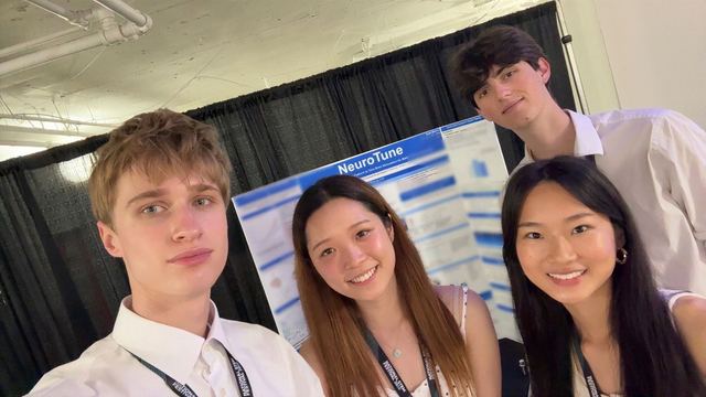 Evan Morris in a selfie with three other students in front of his NeuroTune poster at the National STEM Festival