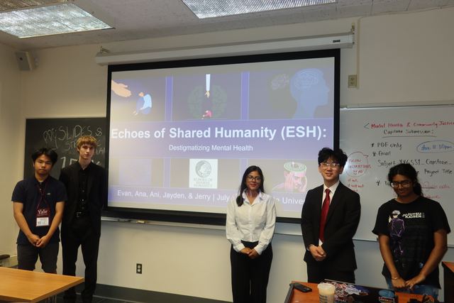 Five students stand in a classroom in front of a projected title slide reading 'Echoes of Shared Humanity (ESH): Destigmatizing Mental Health'; a Yale lanyard is visible, suggesting a summer program capstone presentation