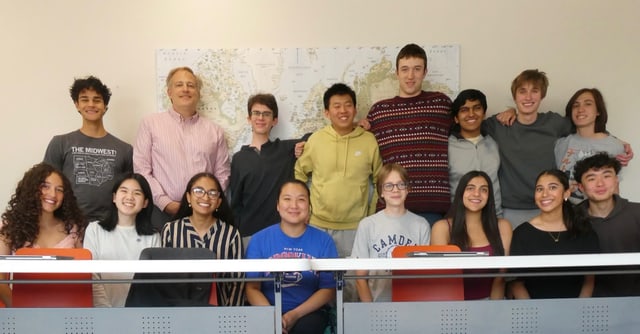 Evan, back row, second from right, in a class photo with his classmates and their teacher in front of a large Arctic-centered world map