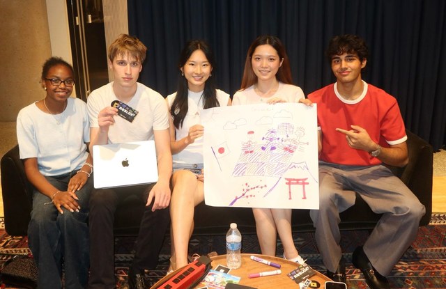 Evan and four others on a couch holding Roblox gift cards and a hand-drawn, Japan-themed game concept poster