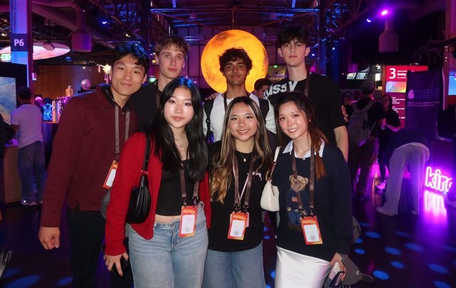 Evan and six others wearing Startup School lanyards beneath a glowing moon installation at a San Francisco event